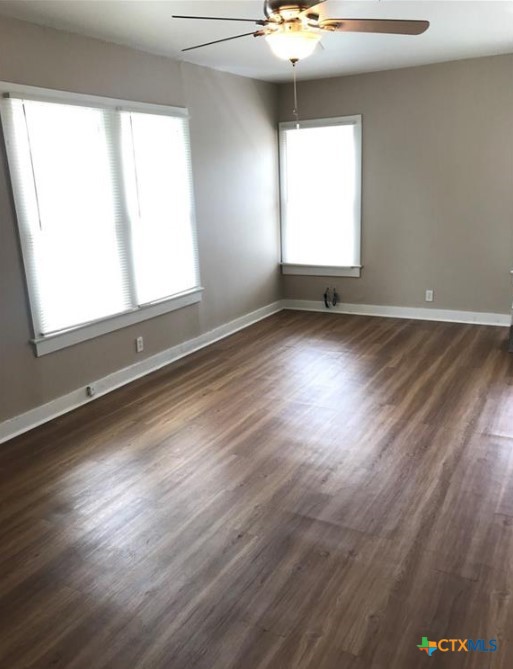 305 East Sabine Street, Unit A Victoria, TX 77901 - Photo 3 of 6 an empty room with wooden floor and windows