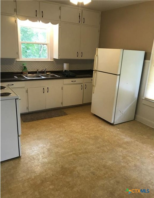 305 East Sabine Street, Unit A Victoria, TX 77901 - Photo 4 of 6 a kitchen with granite countertop a sink a stove a refrigerator a window and a kitchen island