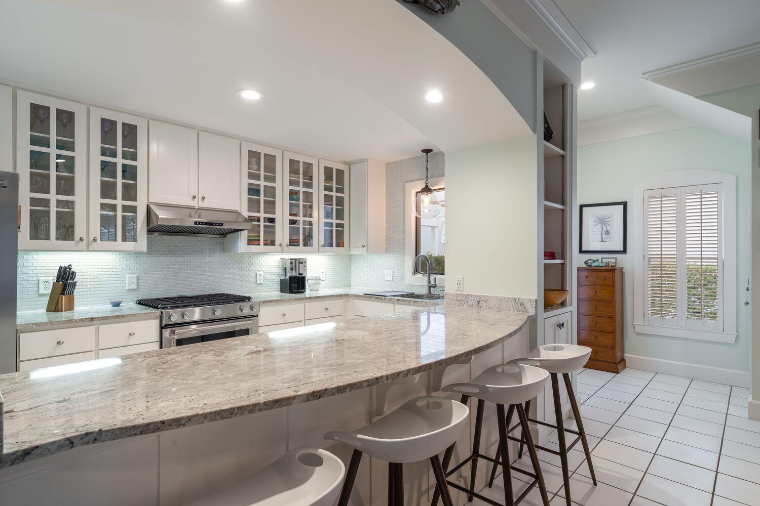 224 Rue Caribe Miramar Beach, FL 32550 - Photo 16 of 67 a kitchen with stainless steel appliances granite countertop a stove a refrigerator a sink and white cabinets with wooden floor