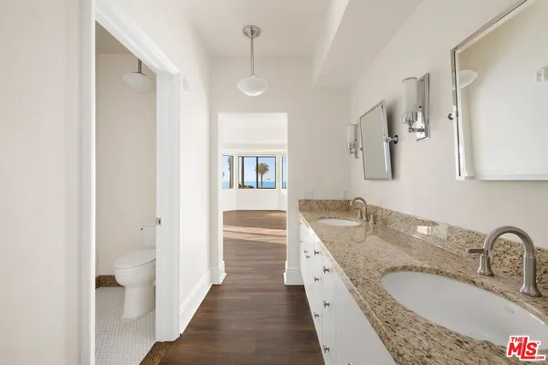 a bathroom with a granite countertop double vanity sink a mirror and a shower