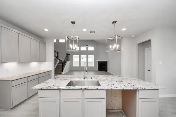a large kitchen with a large counter top a sink stainless steel appliances and cabinets