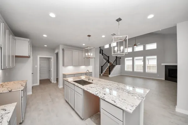 a large white kitchen with granite countertop a sink and cabinets