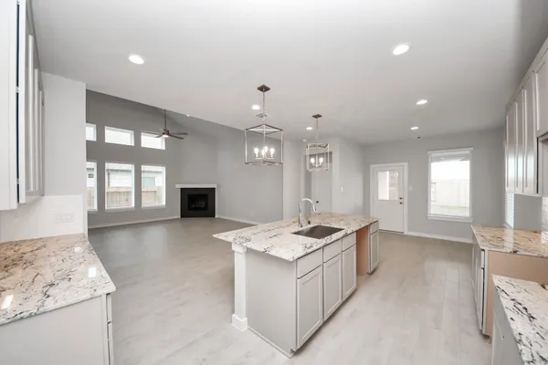 a view of kitchen with granite countertop living room and white cabinets