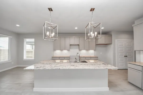 a large kitchen with kitchen island a stove a sink a center island and cabinets
