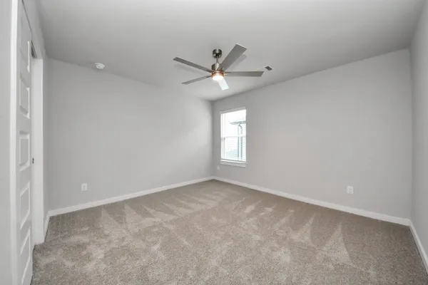 an empty room with a ceiling fan and a carpet