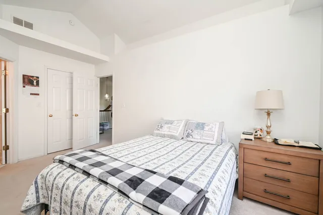 a bedroom with a bed and a lamp on dresser