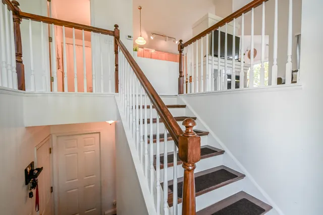 a view of staircase with lots of frames on wall and a window