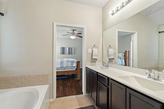 a en suite bathroom with a granite countertop sink and a bathtub