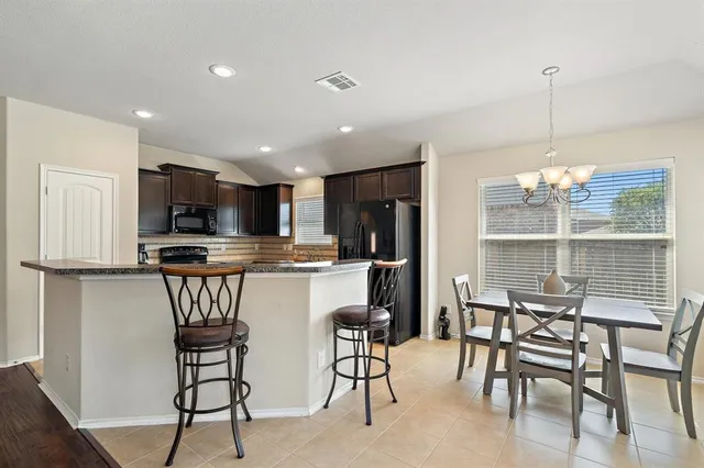 a kitchen with kitchen island granite countertop wooden cabinets and a refrigerator