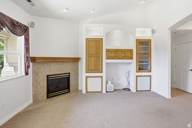 2190 750 West Perry, UT 84302 - Photo 12 of 42 Living area featuring a corner fireplace with a tiled surround and wood mantel, built-in cabinetry with wood-finish doors and shelving, a window with exterior views, and recessed lighting
