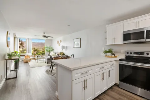 a kitchen with stainless steel appliances a stove a sink dishwasher a microwave oven and a dining table with wooden floor