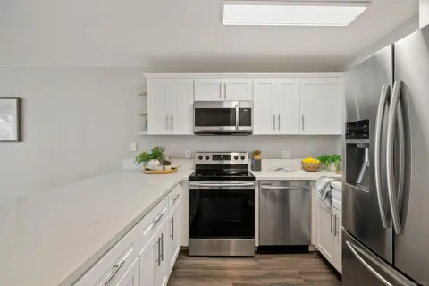 a kitchen with stainless steel appliances a stove a sink a refrigerator a microwave and cabinets