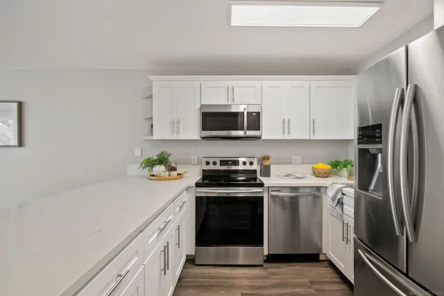 a kitchen with stainless steel appliances a stove a sink a refrigerator a microwave and cabinets