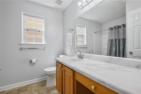 a bathroom with a granite countertop sink toilet and mirror