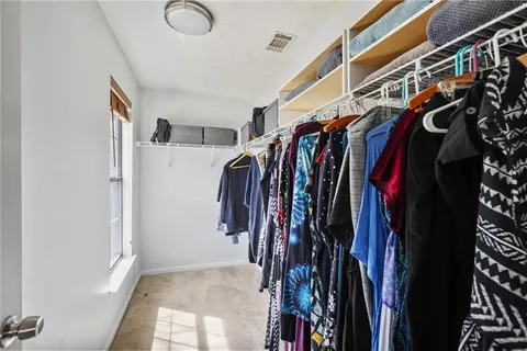 a view of walk in closet with clothes and shoes