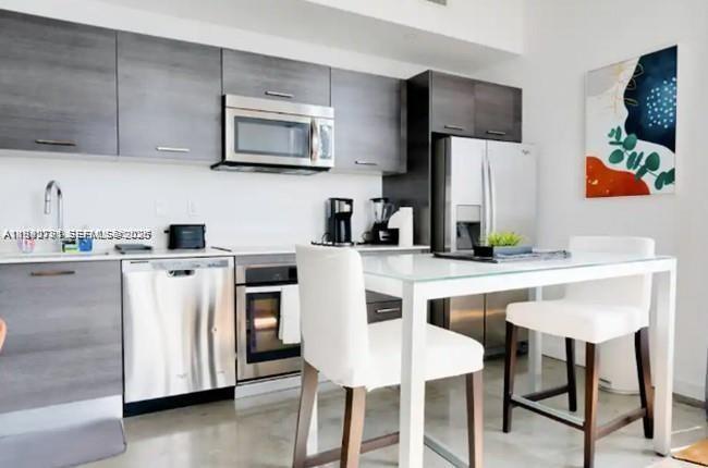 151 Southeast 1st Street, Unit 3111 Miami, FL 33131 - Photo 7 of 35 a kitchen with stainless steel appliances a white table and chairs in it