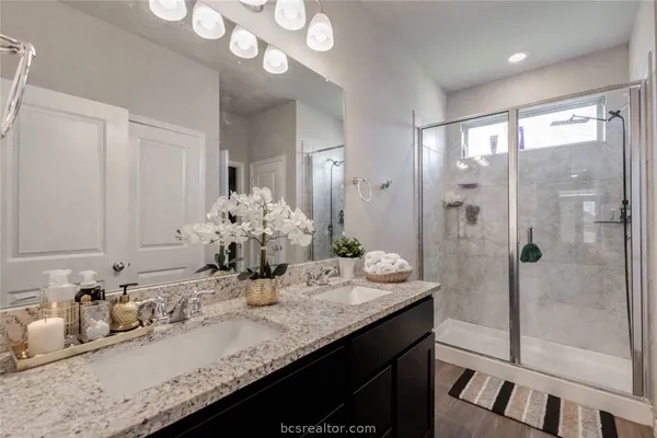 a bathroom with a granite countertop sink a mirror and a shower