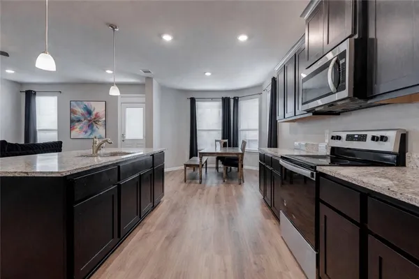 a kitchen with stainless steel appliances granite countertop sink stove top oven and cabinets