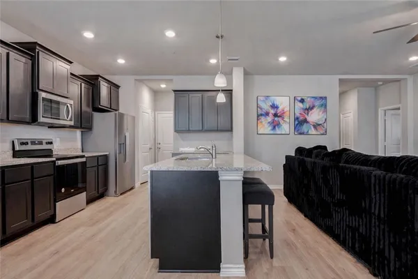 a kitchen with stainless steel appliances kitchen island granite countertop a refrigerator a stove top oven and a sink