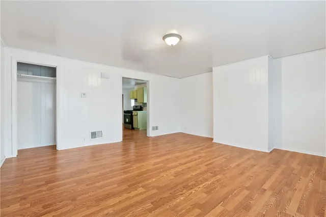 a view of an empty room with wooden floor and a cabinet