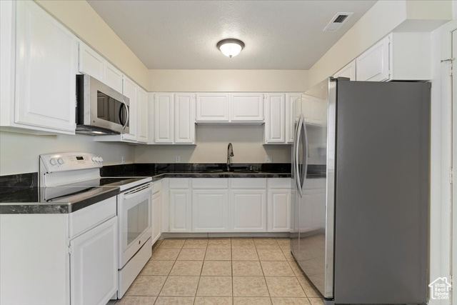 947 Canyon Road South, Unit 15 Ogden, UT 84404 - Photo 9 of 22 Kitchen featuring dark countertops, appliances with stainless steel finishes, white cabinets, and light tile patterned floors