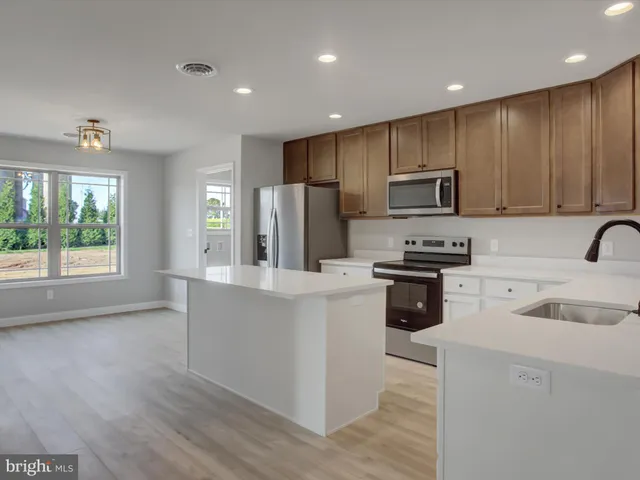 a kitchen with stainless steel appliances kitchen island granite countertop a refrigerator a stove and a sink with wooden floor