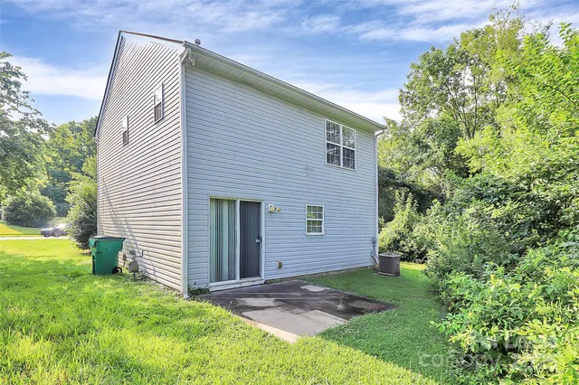 a backyard of a house with plants and large tree