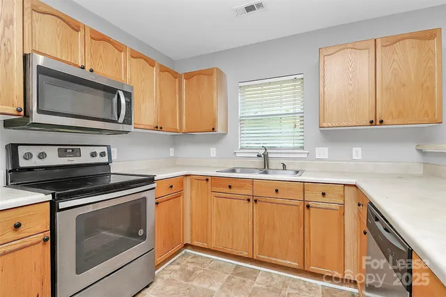 a kitchen with stainless steel appliances granite countertop white cabinets a sink and a stove