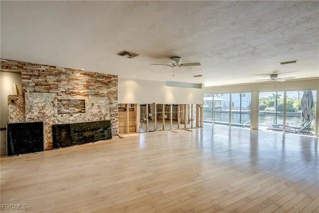 an empty room with fireplace wooden floor and windows