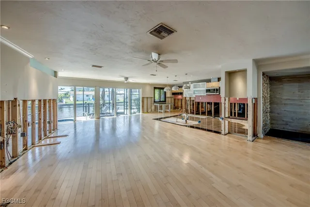 a view of an empty room with wooden floor and windows