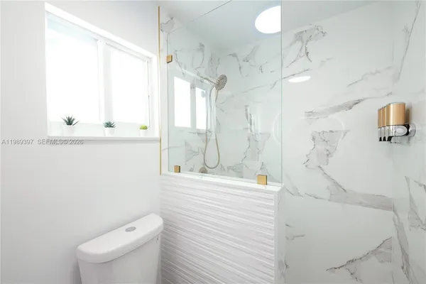 a bathroom with a shower a sink a toilet and a window