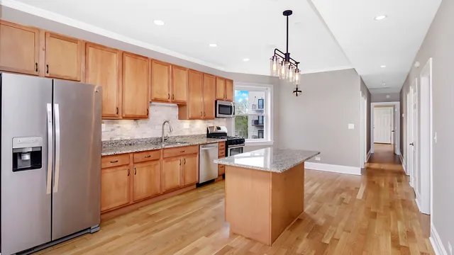 a kitchen with granite countertop a refrigerator a sink dishwasher a stove and white cabinets with wooden floor