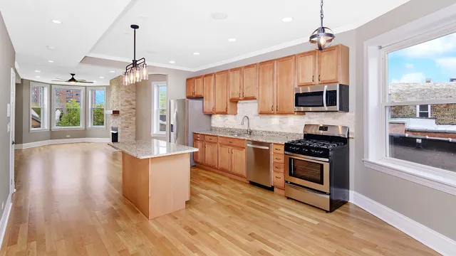 a kitchen with stainless steel appliances a stove top oven a sink dishwasher a refrigerator and a dining table with wooden floor