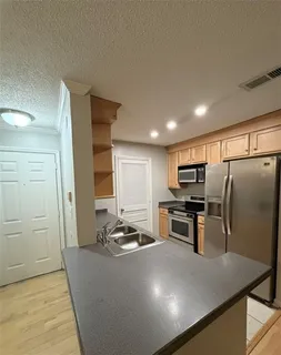 a kitchen with kitchen island a counter top space cabinets stainless steel appliances and a window