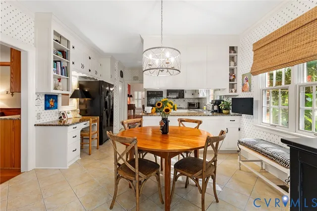 a dining room with stainless steel appliances granite countertop a table chairs and a refrigerator