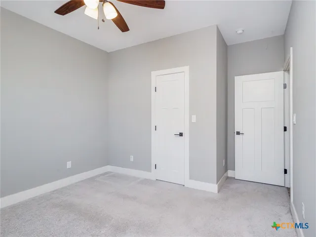 an empty room with a ceiling fan and carpet