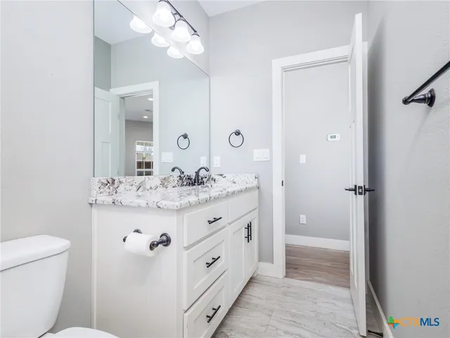 a bathroom with a granite countertop sink a toilet and shower