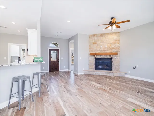 a view of empty room with kitchen and fireplace