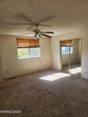 an empty room with windows and a ceiling fan