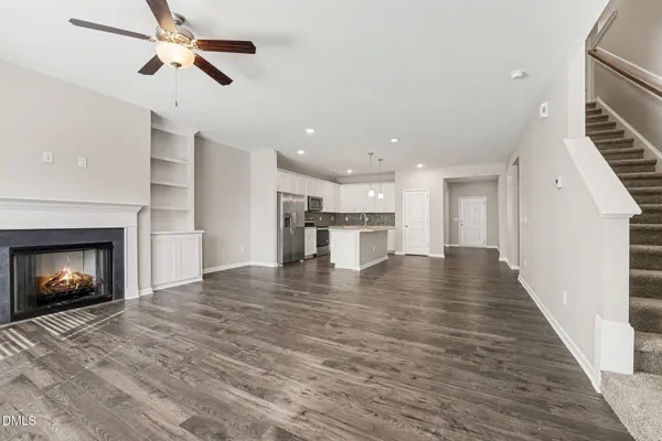 a view of an empty room with wooden floor fireplace and a window
