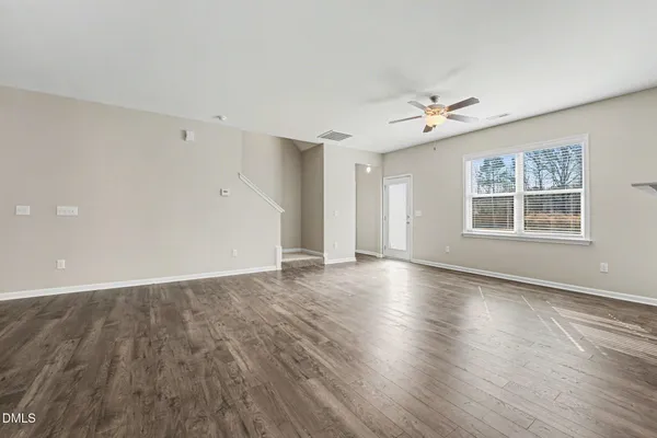 an empty room with wooden floor chandelier and windows