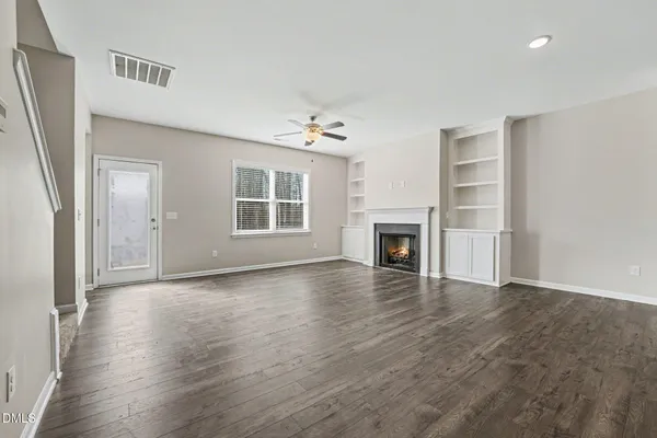 an empty room with wooden floor fireplace and windows