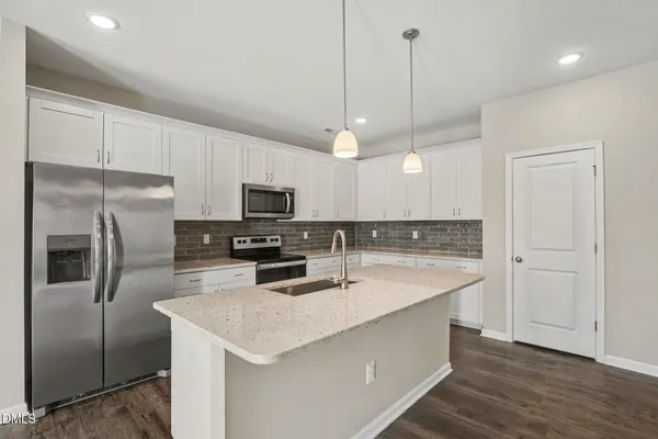 a kitchen with stainless steel appliances granite countertop a sink a stove a refrigerator a center island with wooden floor