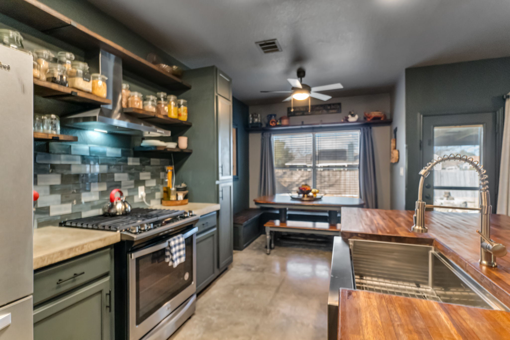 401 Kates Way Hutto, TX 78634 - Photo 12 of 37 Kitchen with stainless steel range with gas stovetop, finished concrete floors, open shelves, ventilation hood, and freestanding refrigerator
