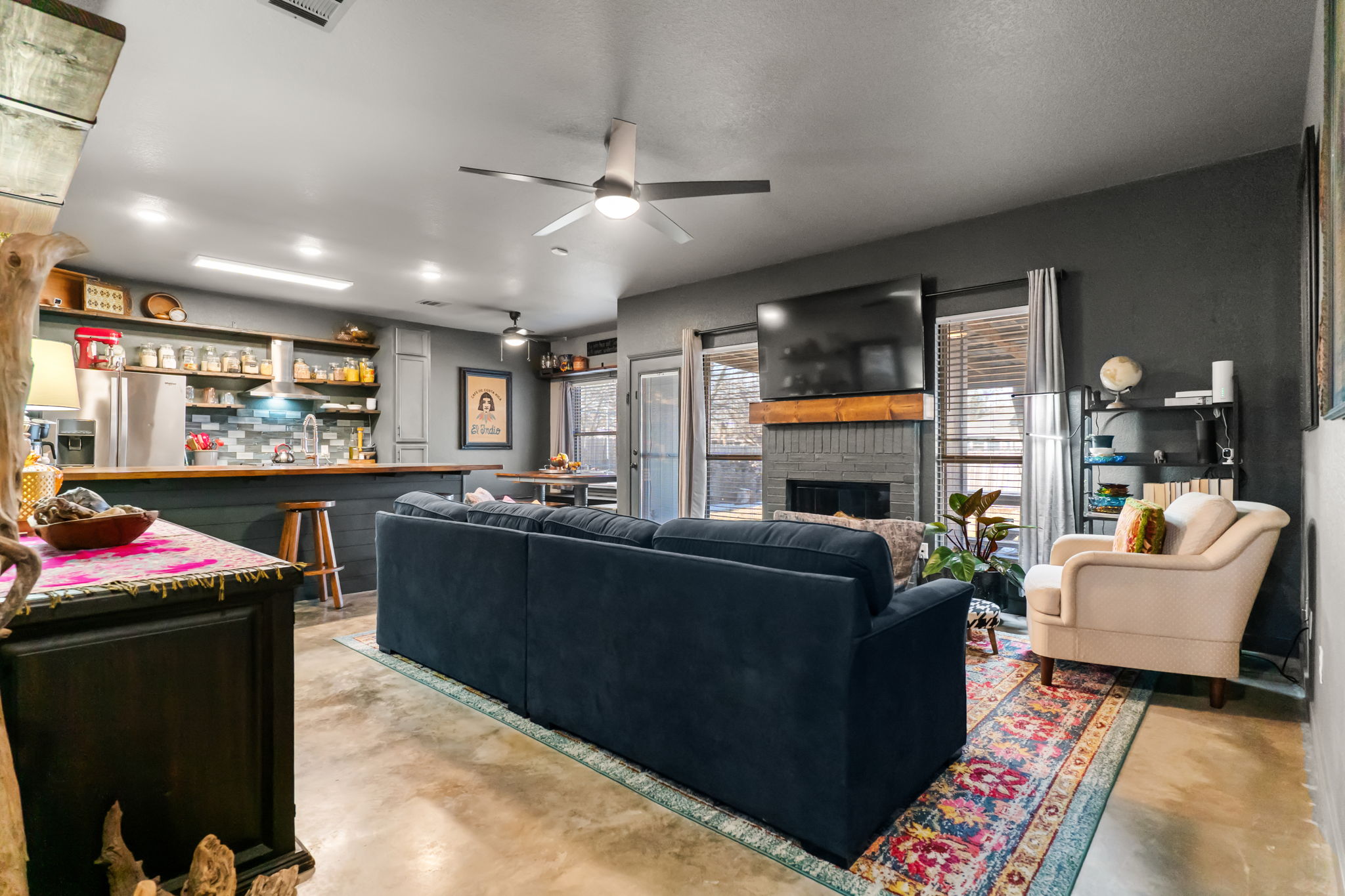 401 Kates Way Hutto, TX 78634 - Photo 5 of 37 Living room featuring finished concrete floors, a fireplace, a bar, and a ceiling fan