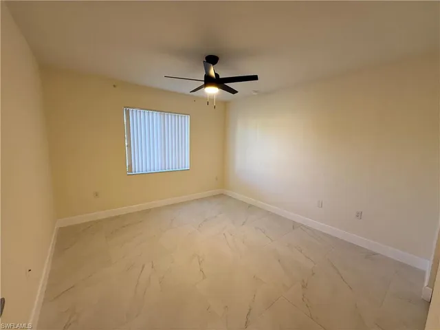 an empty room with a ceiling fan and a window