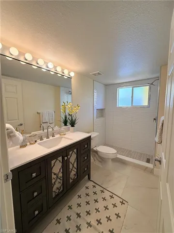 a spacious bathroom with a double vanity sink a toilet and a mirror
