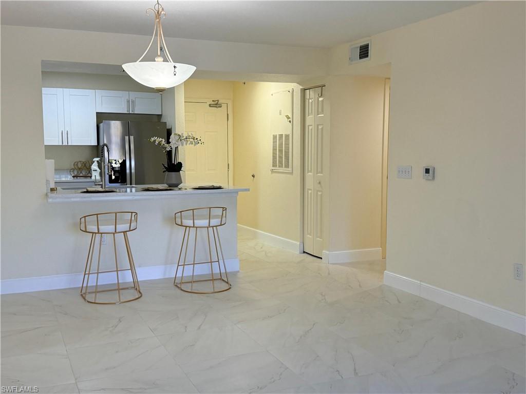 8274 Key Royal Circle, Unit 1012 Naples, FL 34119 - Photo 5 of 20 a kitchen with stainless steel appliances granite countertop a sink and a refrigerator