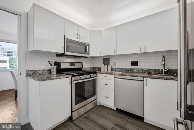 a kitchen with stainless steel appliances granite countertop a stove a sink and a microwave