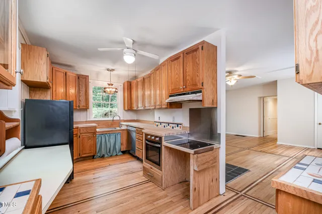 a kitchen with stainless steel appliances granite countertop a stove top oven a sink dishwasher and a refrigerator with wooden floor